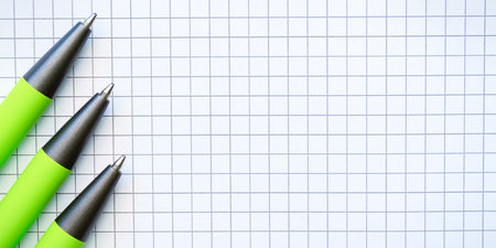 Three Green pens on the checkered piece of paper. High quality photo