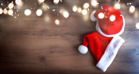 Two blurred santa claus hats on a wooden background with defocused lights. Festive christmas concept with place for text. High quality photoの写真素材