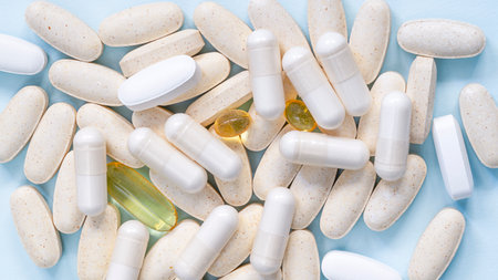 Blurred White and yellow pills spread on Blue. Health insurance concept. Vitamins and supplements...