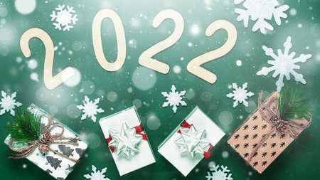 Christmas composition made of Christmas decoration and 2022 numbers on green background. Minimal...