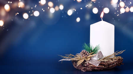 Blurred winter Christmas composition with one burning candle on Blue background with Light and Snow. New year concept with copy space. High quality photoの写真素材