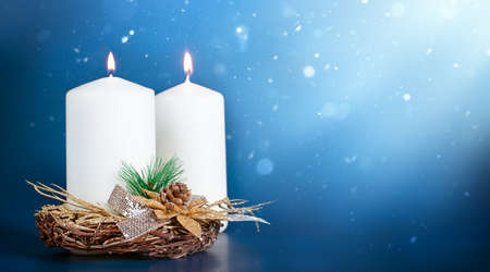 Blurred winter Christmas composition with two burning candles on Blue background with Light and Snow. New year concept with copy space. High quality photoの写真素材