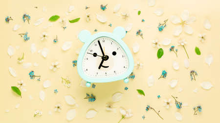 Summer composition with from flowers and clock, alarm on yellow background. Flat lay, top view. high quality photoの写真素材