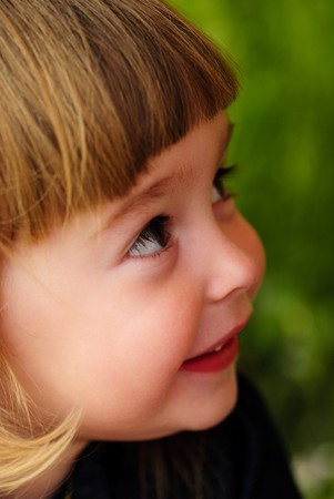 Little girl's face with hands and smile. Close up soft portrait on nature. Shalllow DOF. Focus on right eyeの写真素材