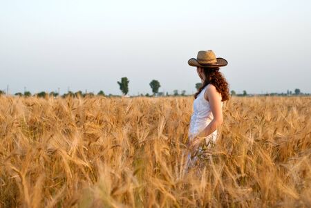 Girl in wheat field in white dress and hat. Selective focus.