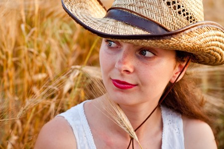 Girl in wheat field in white dress and hat. Selective focus.の写真素材
