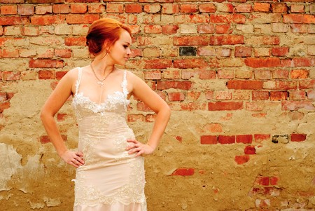 Glamour bride in beige dress stand near the old wall with ivyの写真素材