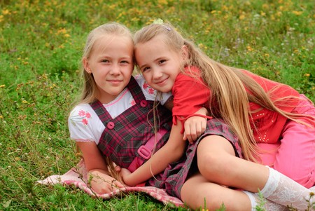 Two sisters hug one another outdoors, happy familyの写真素材