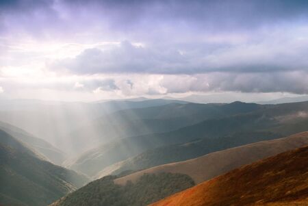 Sunrays through the clouds on the sky in mountains range