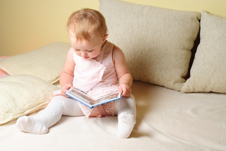 Little girl are readign the book, sitting on the sofaの写真素材