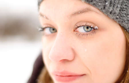 Girl's face with blue eyes under snow outdoors. Close up portraitの写真素材