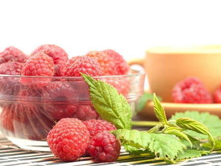 Still life with raspberries and green leafs on striped placemat with white copyspace, close upの写真素材