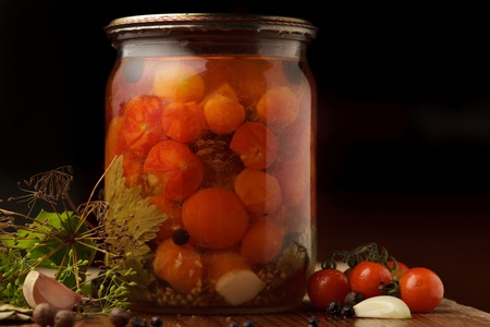 Still life of preserving tomatoes on wooden table in kitchen