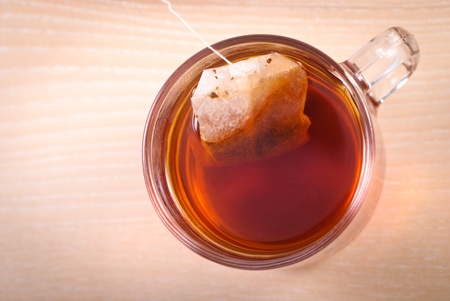 teabag in cup with tea on wooden tableの写真素材