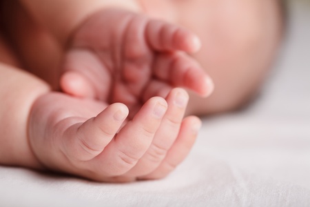 Tiny fingers of newborn baby in mother handの写真素材