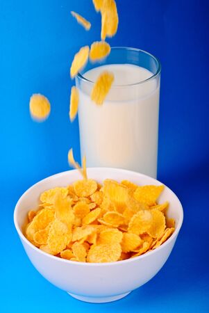 Breakfast from milk and pouring  cornflakes over blue backgroundの写真素材