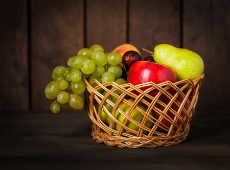 Basket of fruits on wood background closeupの写真素材