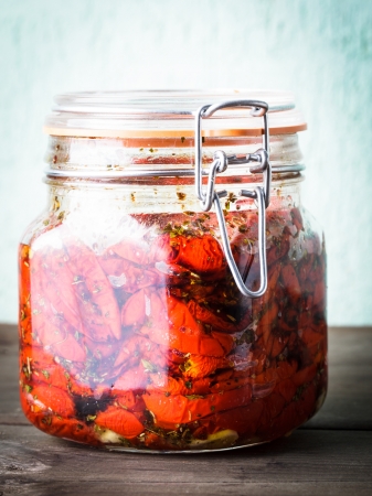 Sun dried tomatoes with herbs and olive oil in jarの写真素材