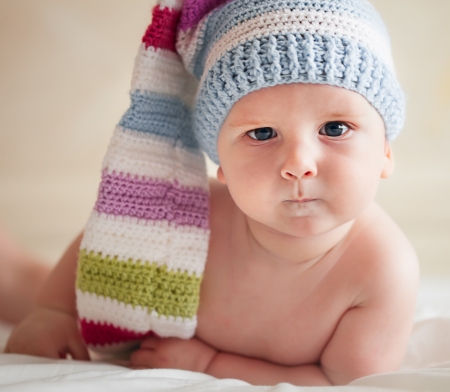 Baby in funny crochet hat lying on the badの写真素材