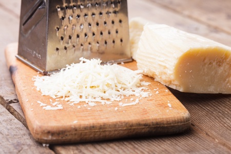Grated Parmesan cheese with grater on a tableの写真素材