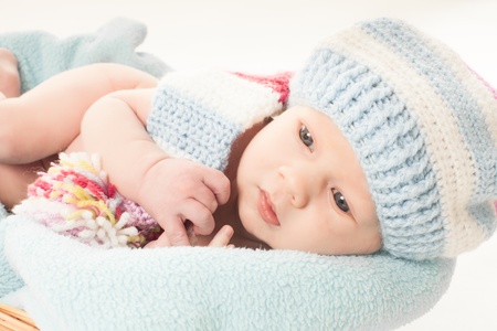 Newborn baby boy in the crochet hat lay in basketの写真素材