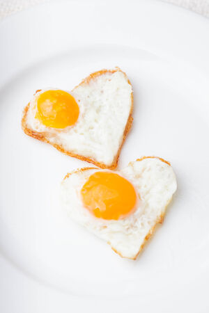 Heart shape fried eggs on the white plateの写真素材
