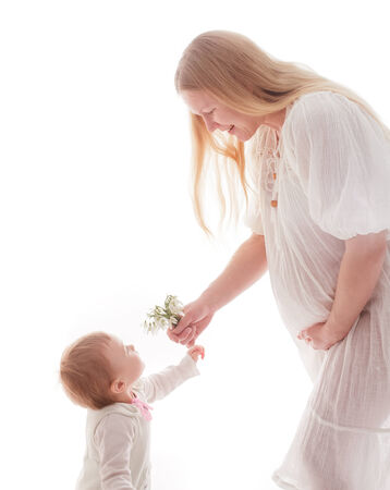 Girl gives snowdrops to pregnant mother, isolated on whiteの写真素材