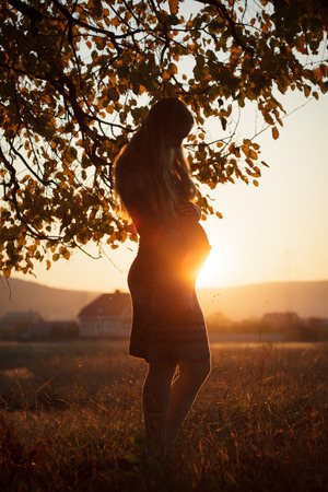 Pregnant walking woman outdoors on the sunsetの写真素材