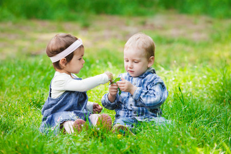 Little kids play outdoors on the grassの写真素材