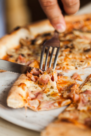 Man eats pizza. Close up pizza with fork and knifeの写真素材