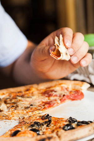 Man eats pizza. Close up pizza piece in handの写真素材