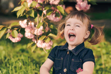 Adorable little girl's portrait in the garden, sakura blossomの写真素材