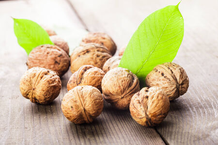 Walnuts with shell and green leaf on the wooden tableの写真素材