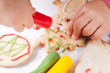 Hands of little girl, who draws on gingerbread cookiesの写真素材