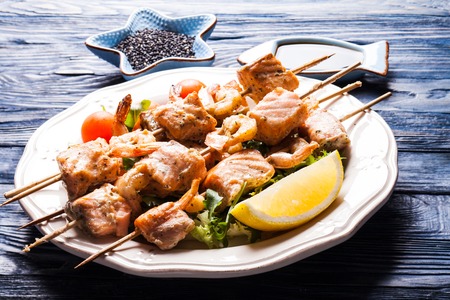 Seafood shashlik - slices of salmon and shrimps on a wooden skewersの写真素材