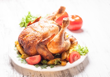 Whole Roasted Chicken on a plate with fried potatoesの写真素材