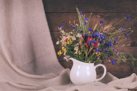 Wildflowers in white ceramic jug and cups on trayの写真素材