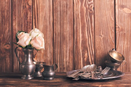 Still life with antique cutlery, plate and flowers in tin jugの写真素材