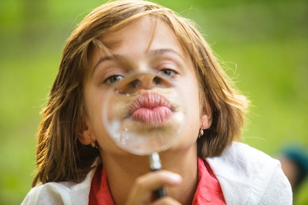 Close-up portrait of a girl that plays with magnifying glassの写真素材