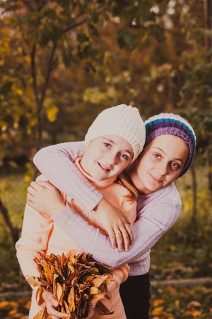 Two friendly sisters playing in autumn and smilingの写真素材