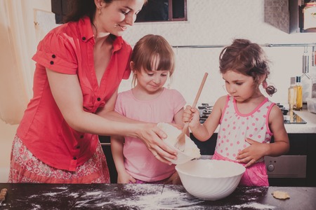Mom is baking cookies with her kids at home kitchen
