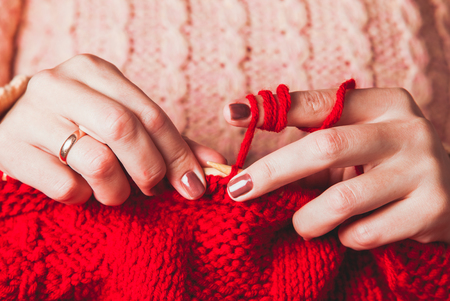The hands that hold needles and knitting a red warm jacketの写真素材