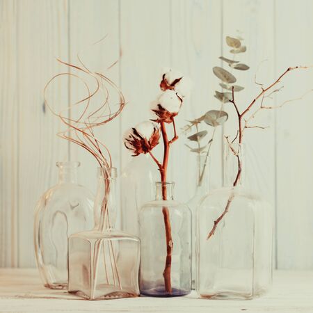 Group decorative branches in glass bottles on wooden backgroundの写真素材