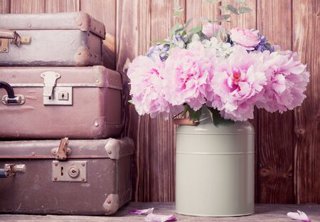 Flowers in a green vintage can and retro suitcasesの写真素材