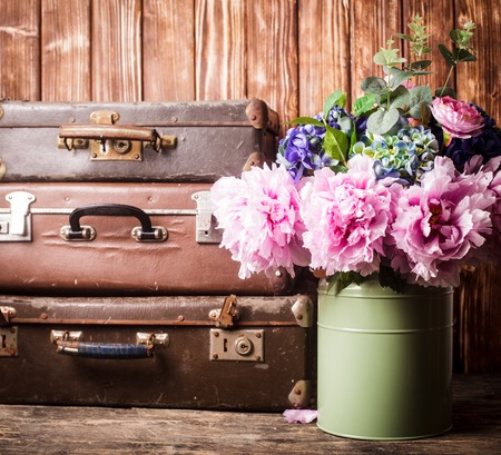 Flowers in a green vintage can and retro suitcasesの写真素材