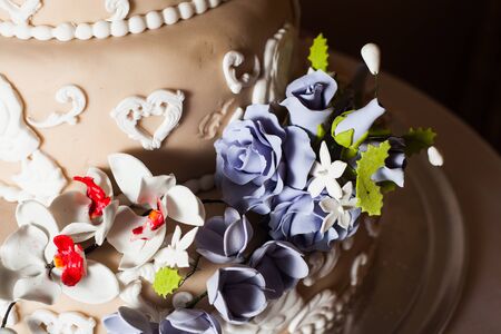 Three-storied wedding cake with violet flowers on a glass standの写真素材