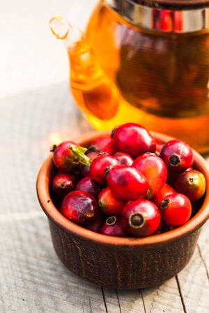 Glass kettle with tea and bowl with berry of a dogroseの写真素材