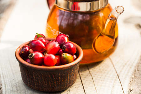 Glass kettle with tea and bowl with berry of a dogroseの写真素材