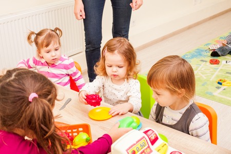 Children playing with housewares and artificial fruit in kindergarten