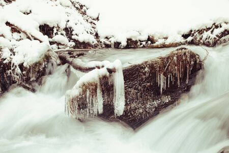 Waterfall mountain river in a forest in winterの写真素材